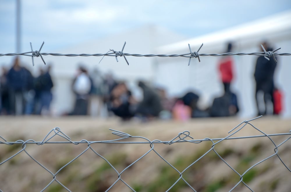 Barbed,Wire,In,Refugee,Camp.,Migrants,Behind,Chain,Link,Fence